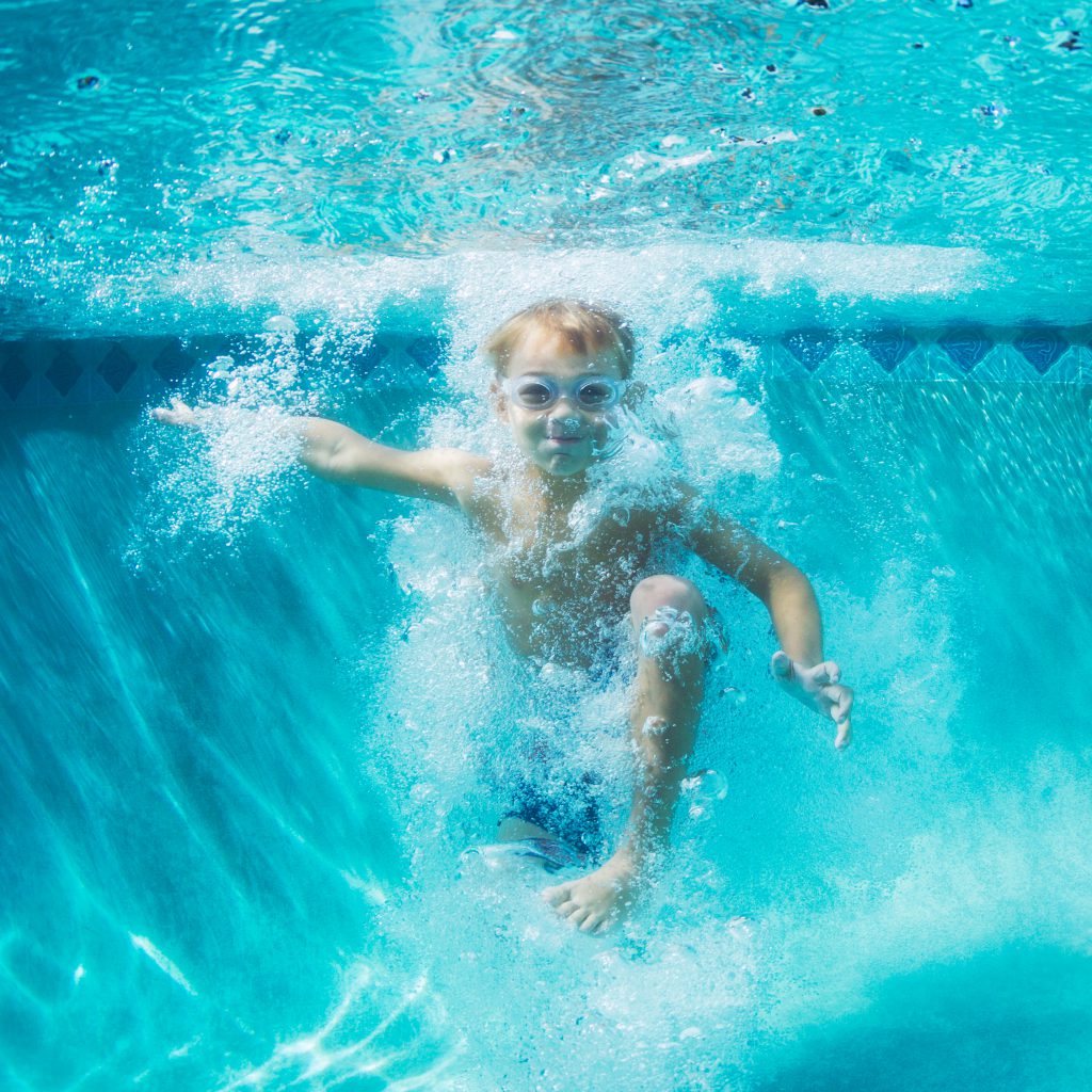 Underwater Young Boy Fun in the Swimming Pool with Goggles. Summer Vacation Fun.